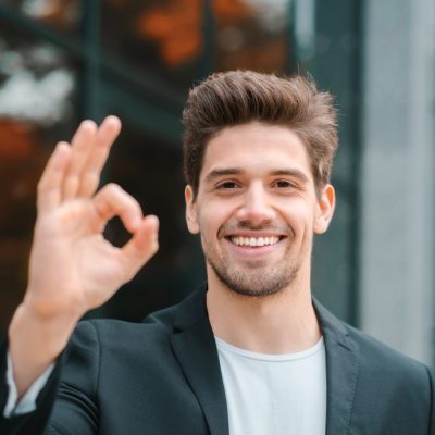 successful-happy-man-looking-to-camera-and-showing-ok-sign-on-office-building-background-professional_t20_R6NmXa